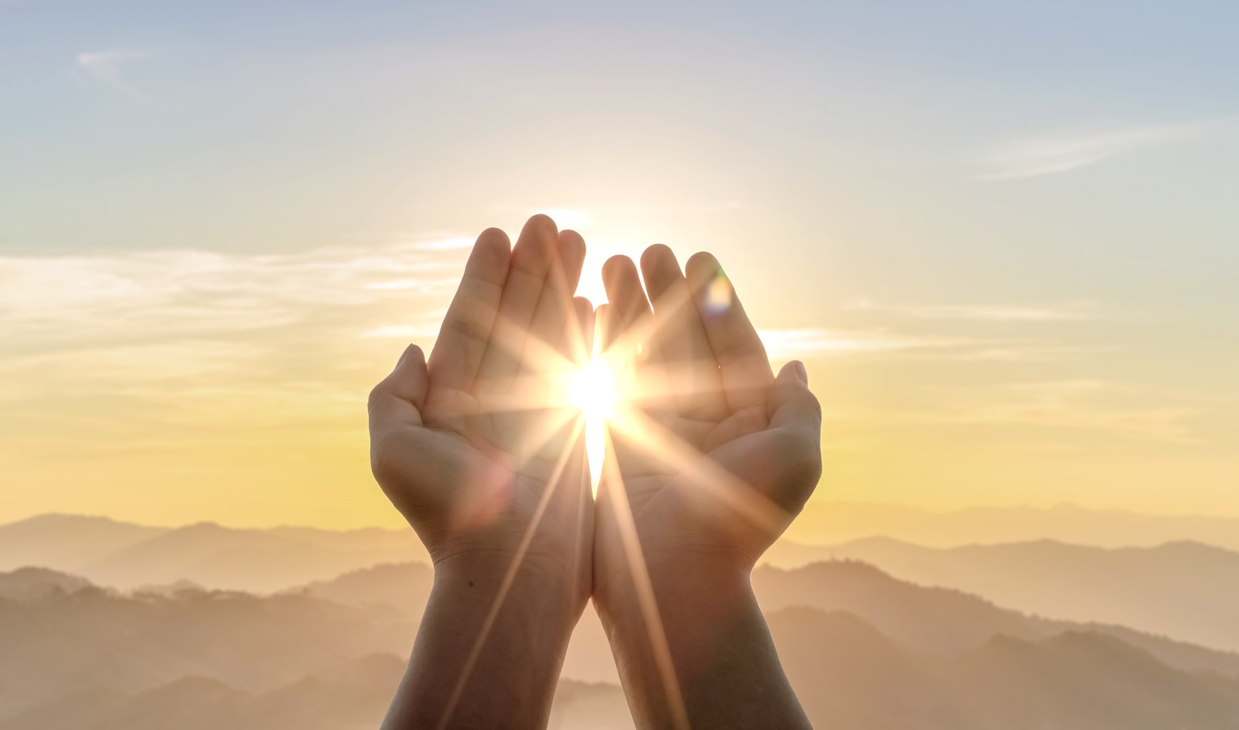 Geöffnete Hände, dazwischen die aufgehende Sonne